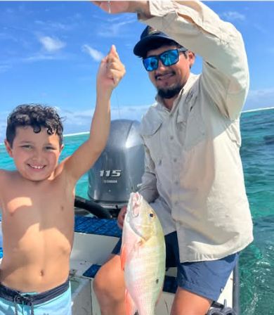 Guide and young guest holding up a mutton snapper caught on the reef