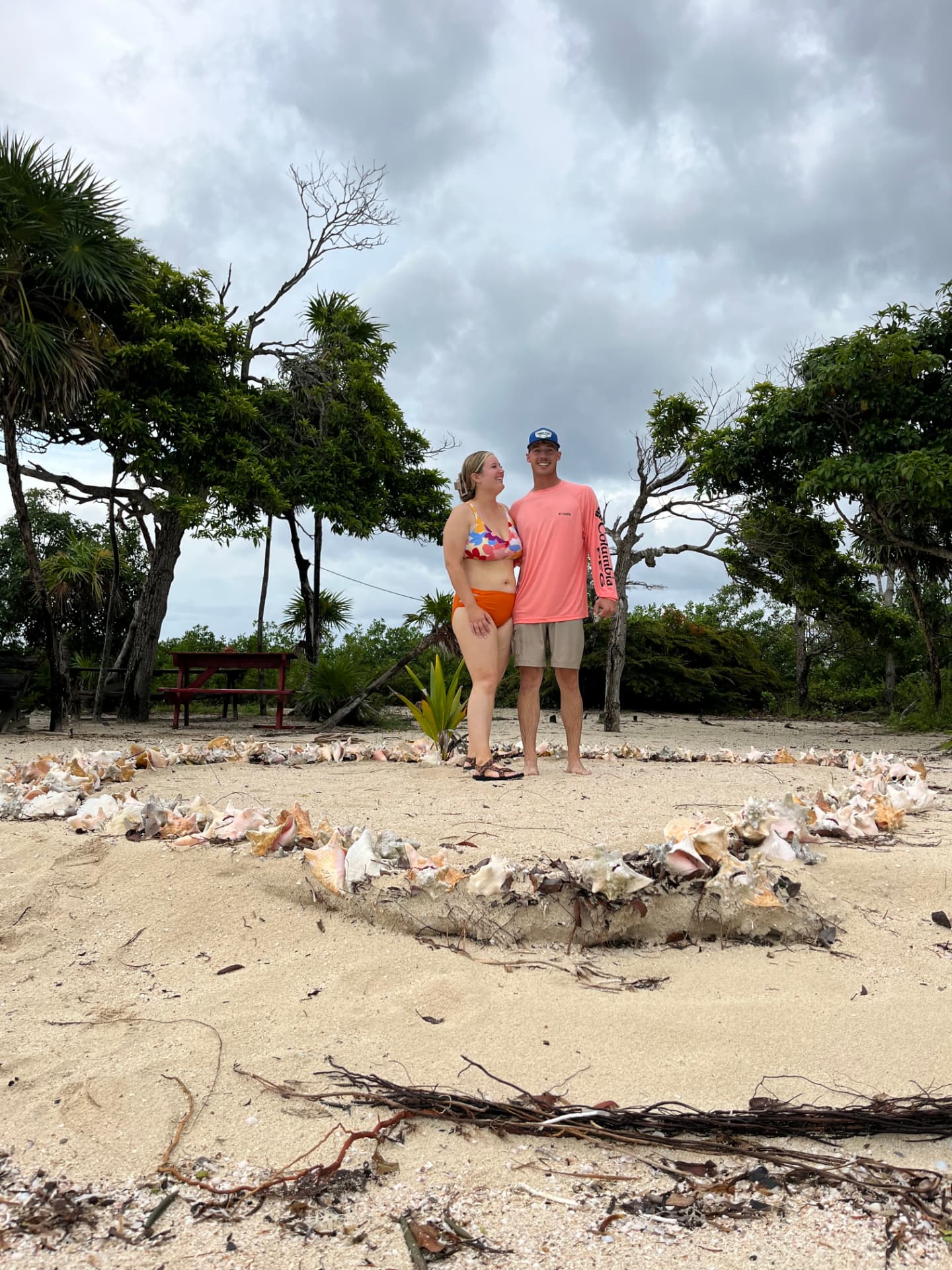 Couple standing inside a conch shell circle on a quiet island beach