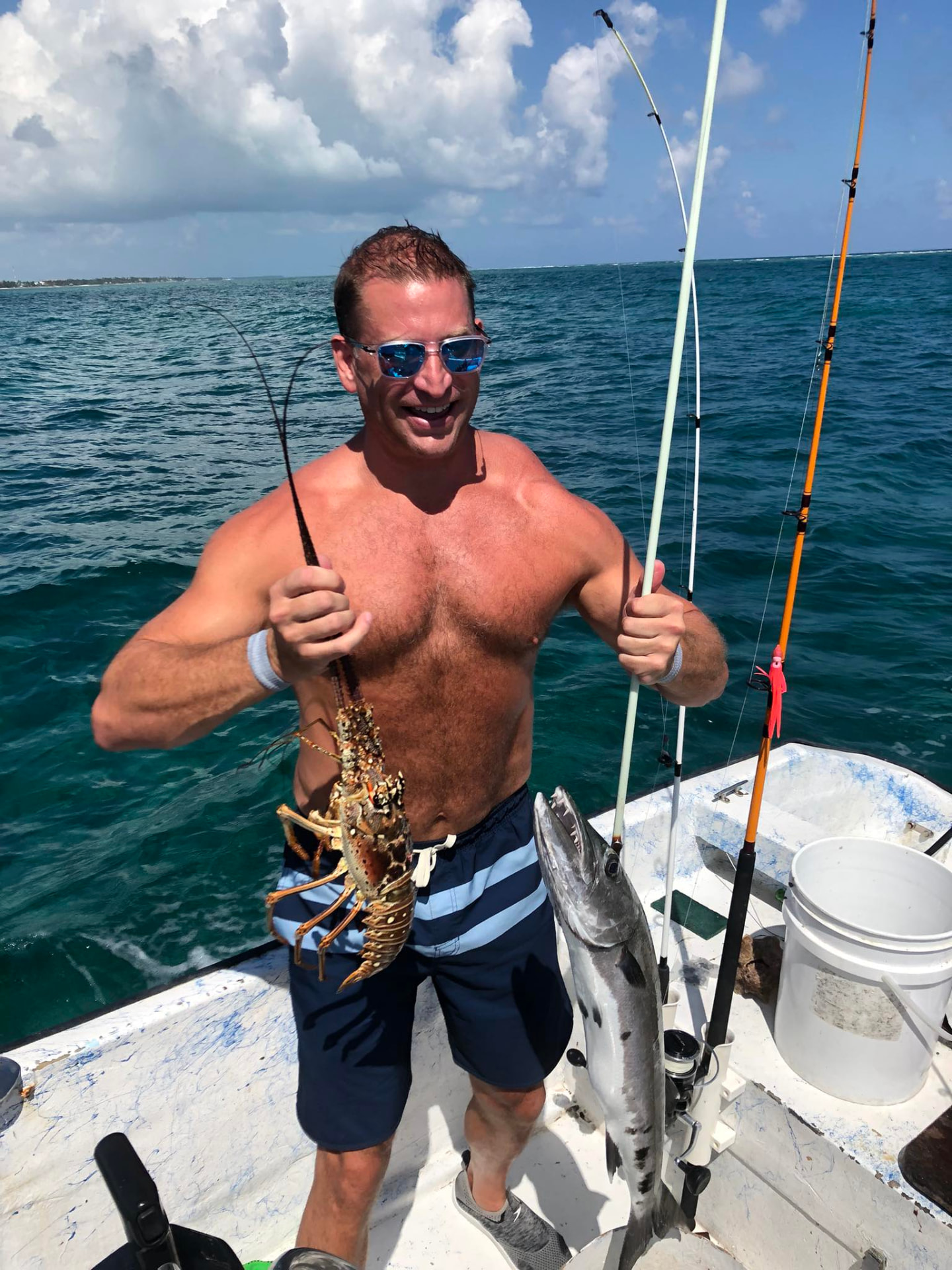 Guest showing off a spiny lobster with a barracuda on deck