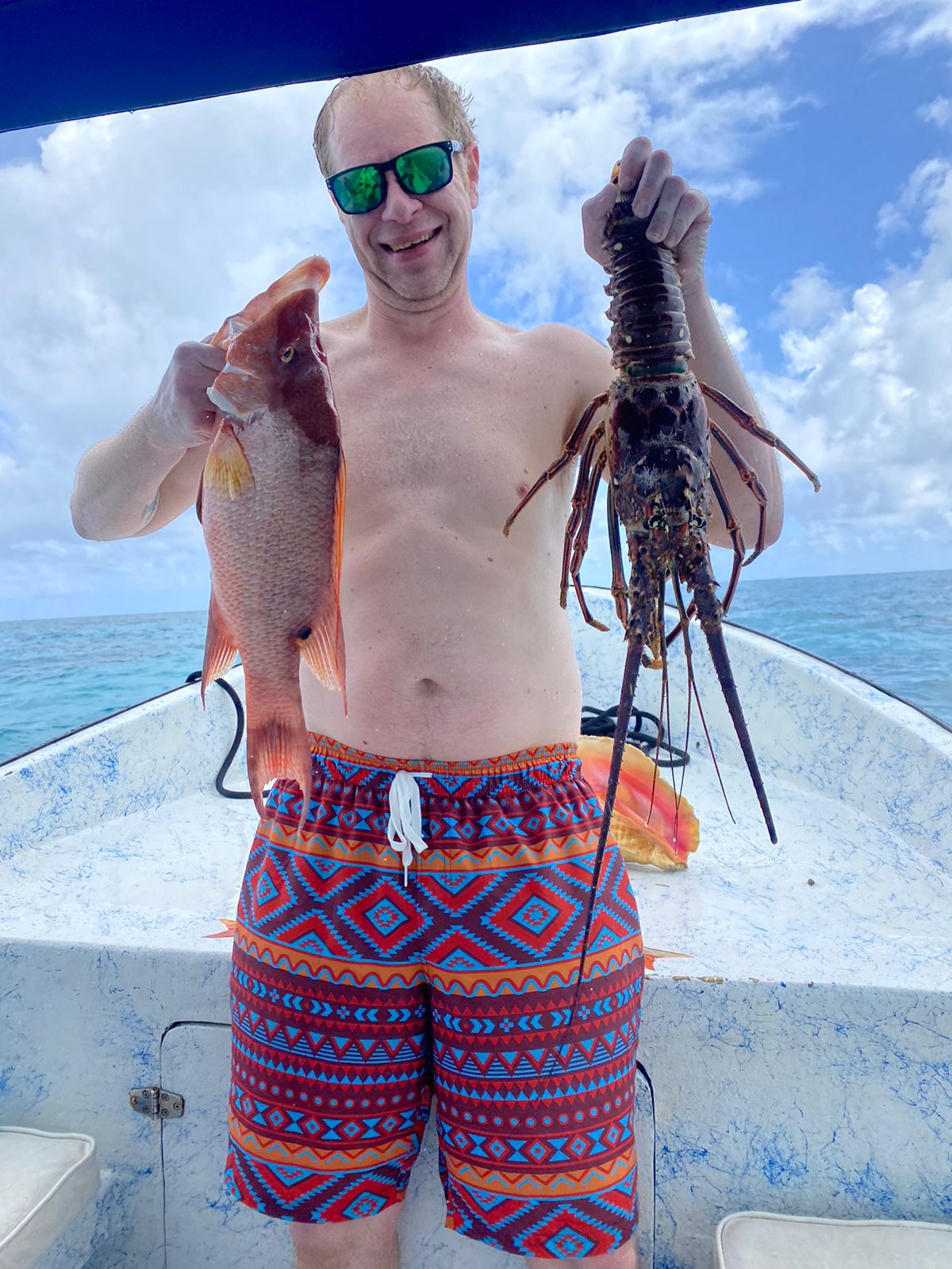 Guest holding a hogfish and a spiny lobster on board