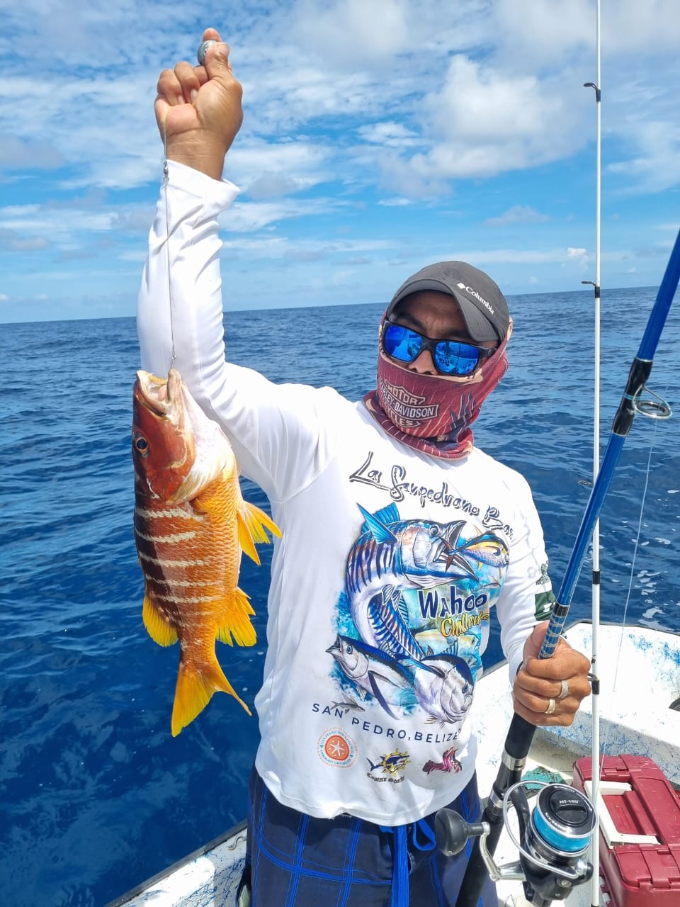 Guide holding a bright yellowtail snapper caught in deep blue water