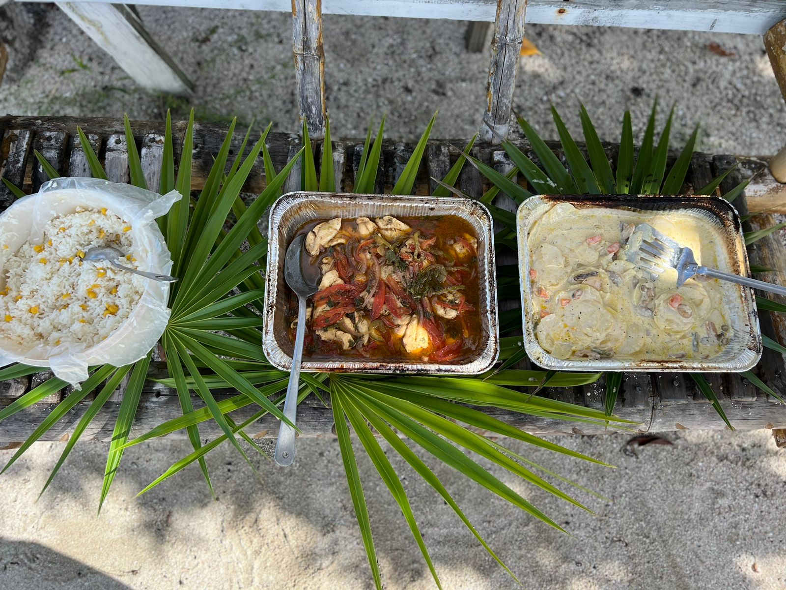 Beach lunch of rice, stew chicken and creamy fish served on palm leaves