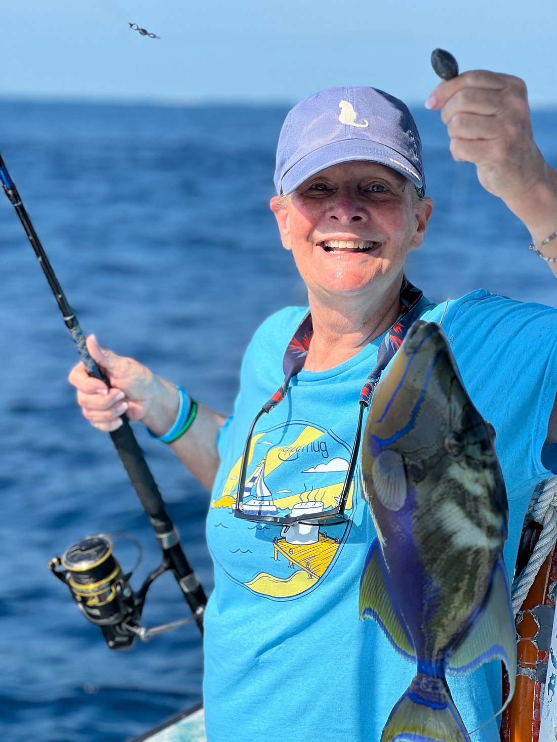 Guest smiling with a colorful triggerfish caught on the reef
