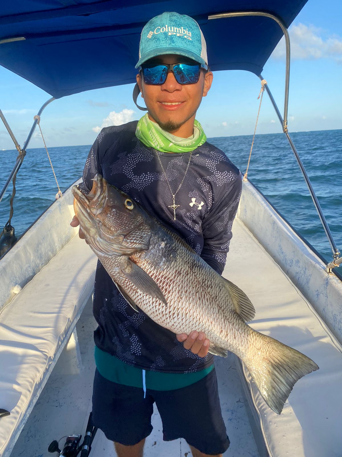 Guide holding a large mangrove snapper on board at sunset