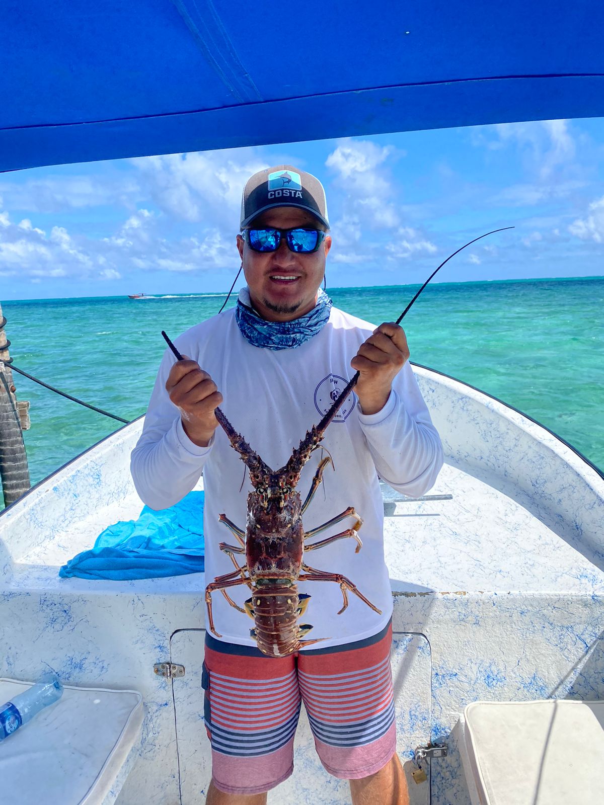 Guide holding up a Caribbean spiny lobster on the boat